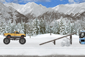 En gul monstertruck står i en snötäckt vintermiljö framför skog och berg, vid en ramp bredvid en blå lastbil