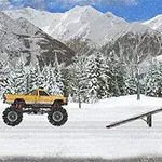 En gul monstertruck står i en snötäckt vintermiljö framför skog och berg, vid en ramp bredvid en blå lastbil