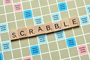 Bräde med bokstäverna som stavar ordet SCRABBLE på träbrickor, omgiven av rutor med olika poängmultiplikatorer