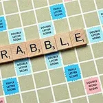 Bräde med bokstäverna som stavar ordet SCRABBLE på träbrickor, omgiven av rutor med olika poängmultiplikatorer